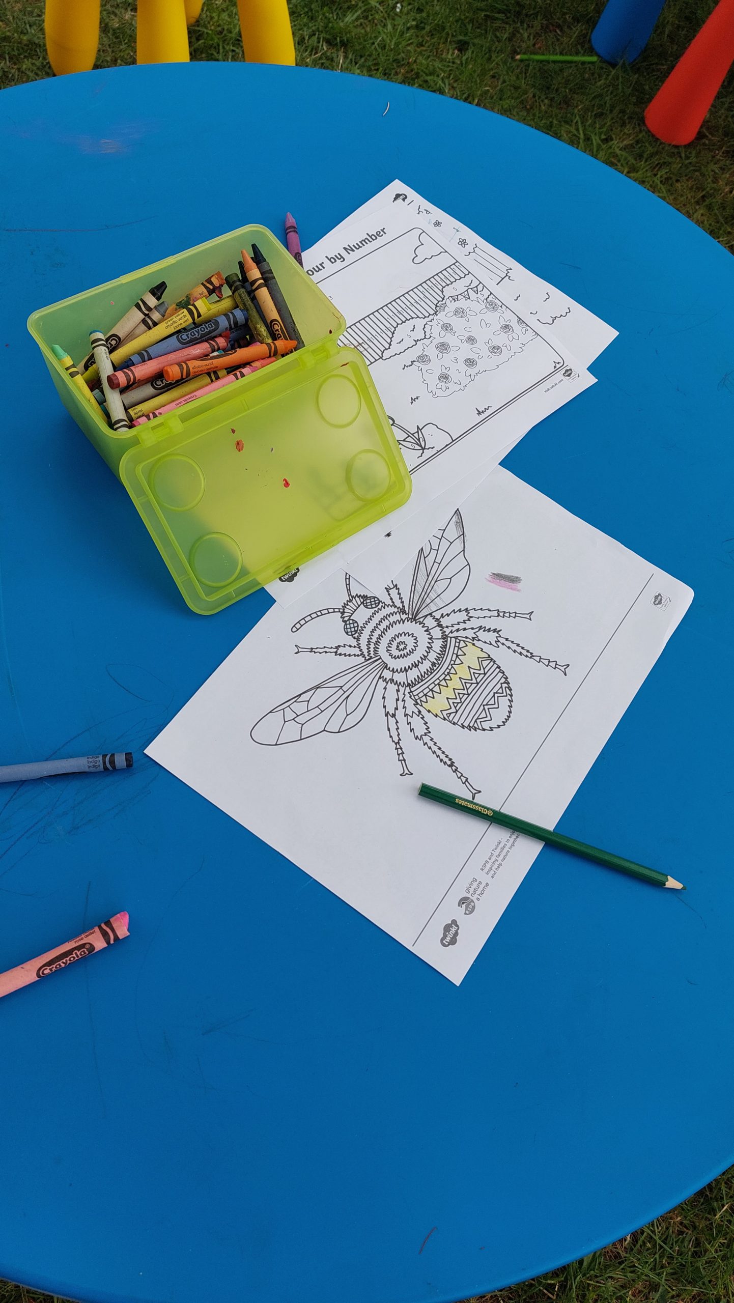 Some crayons and a colouring sheet with a bee on for children to colour in